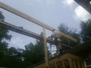 Carpenter setting a ridge beam over a new addition frame — Ice Dam Removal by Roofing Brothers in Vining