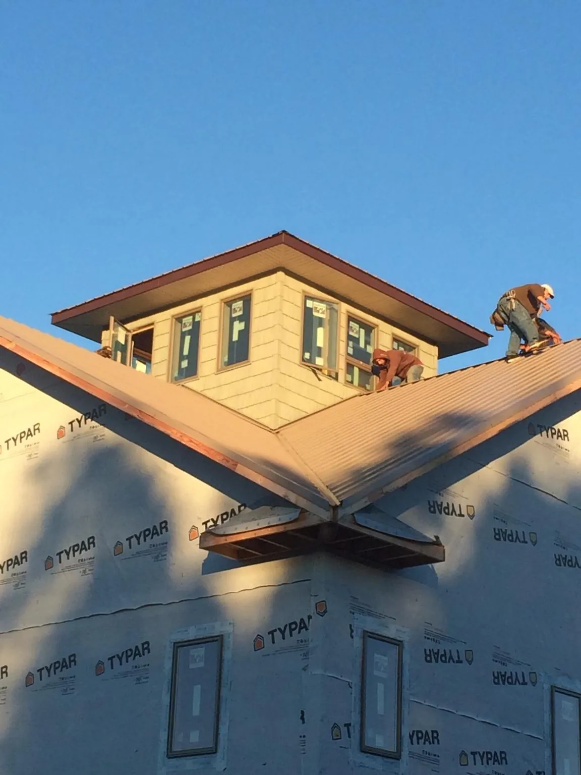 Roofers working around a rooftop cupola on a new metal roof at sunset — Roof Waterproofing in Vining by Roofing Brothers